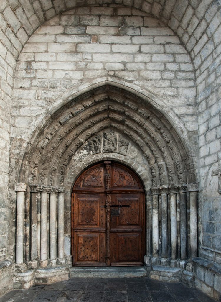 Possibly medieval door positioned under an arch with pillars (we do not service medieval doors)