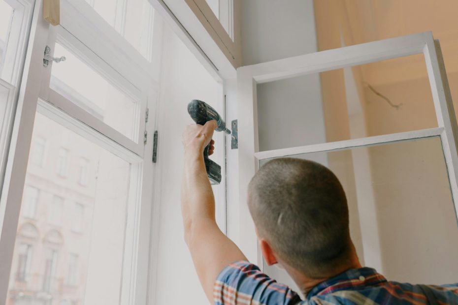Man screwing screws into window hinge with wireless drill